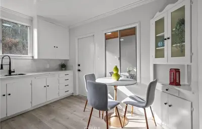 a kitchen with white cabinets and a table and chairs at Modern 2-Bedroom in Santa Moinca Area Close to UCLA in Los Angeles