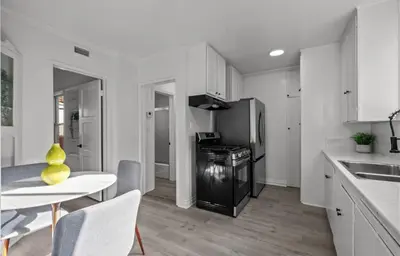 a kitchen with white cabinets and a table and a table and chairs at Modern 2-Bedroom in Santa Moinca Area Close to UCLA in Los Angeles