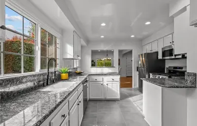 a kitchen with white cabinets and granite counter tops at Modern 2-Bedroom in Santa Moinca Area Close to UCLA in Los Angeles