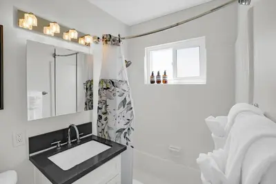 a white bathroom with a sink and a mirror at 6th Haven, Arcade, King Bed, Games, 1 Mile to Beaches in Long Beach