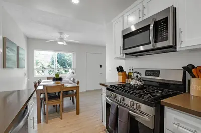 a kitchen with a stove top oven next to a table at 6th Haven, Arcade, King Bed, Games, 1 Mile to Beaches in Long Beach