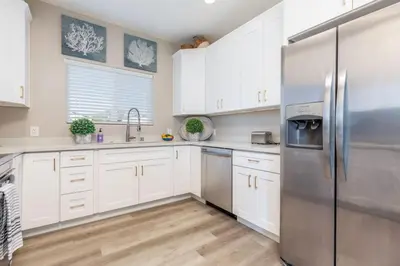 a kitchen with white cabinets and a stainless steel refrigerator at Comfy and Stylish 4 Bathrooms 26 in Ridgecrest