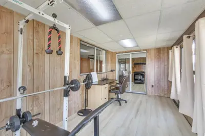 a gym with wood paneling and a room with a desk at Pet-Friendly Ridgecrest Home Near OHV Trails! in Ridgecrest