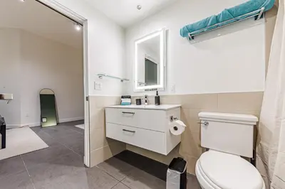 a bathroom with a toilet and a sink and a mirror at Downtown Escape - 2BR w Skyline Views & Hot Tub in Los Angeles