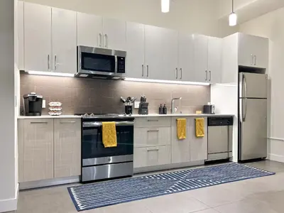 a kitchen with white cabinets and stainless steel appliances at Luxury 2BR in DTLA w Jacuzzi & Rooftop Views in Los Angeles