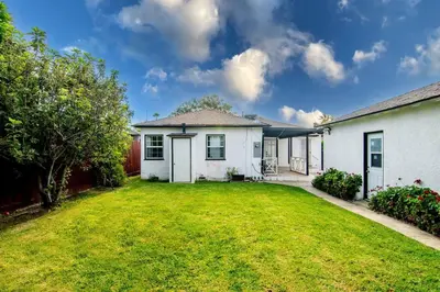 a white house with a yard with a grassy yard at Updated 3-Bedroom LA Home with Backyard, BBQ & Family-Friendly Amenities in Los Angeles