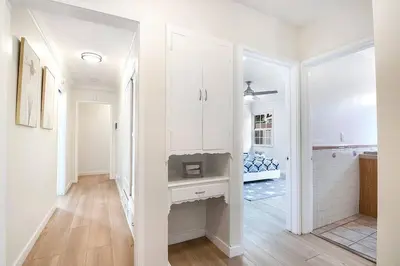 a kitchen with white cabinets and a hallway with wood floors at Updated 3-Bedroom LA Home with Backyard, BBQ & Family-Friendly Amenities in Los Angeles