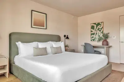 a bedroom with a large white bed and a desk at City Center Hotel By Kasa in Long Beach