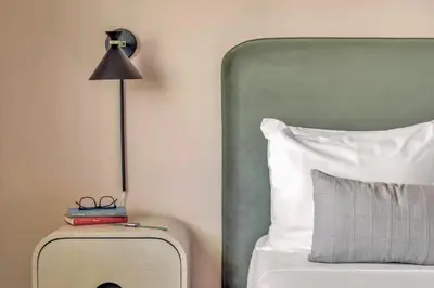 a bed with a suitcase next to a pillow and a lamp at City Center Hotel By Kasa in Long Beach