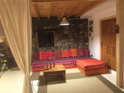 a couch in a living room with a stone wall at Hilgard House Westwood Village in Los Angeles