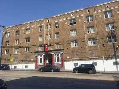 a large brick building with cars parked in front of it at Stuart Hotel in Los Angeles