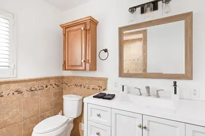 a bathroom with a toilet and a sink and a mirror at Modern Oasis with Pool & Jacuzzi near Universal Studios in Los Angeles