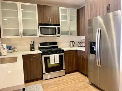 a kitchen with stainless steel appliances and wooden cabinets at 1 Bedroom XL Condo with King bed, Garden View, Parking Included in Los Angeles