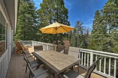 a wooden table and chairs on a deck with an umbrella at Lake Arrowhead Fishermans Haus in Lake Arrowhead