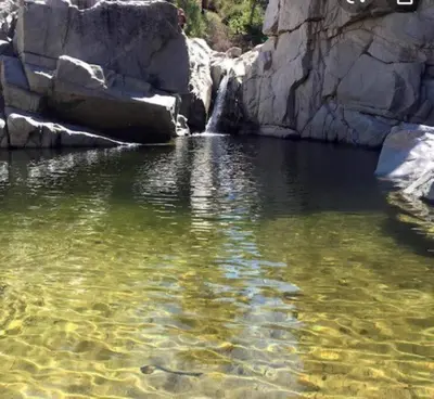 a body of water with a waterfall and rocks at The Muddy Moose- Spacious Family Getaway in Lake Arrowhead
