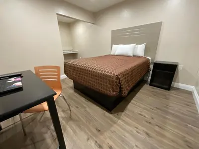 a bedroom with a bed and a table and a desk at State Motel in South Gate
