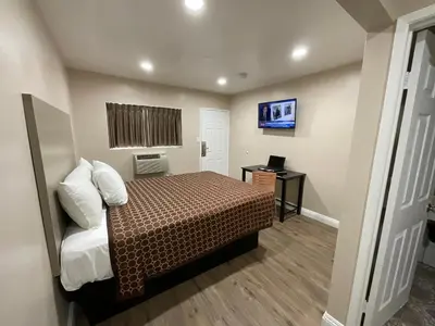 a small bedroom with a bed and a desk at State Motel in South Gate