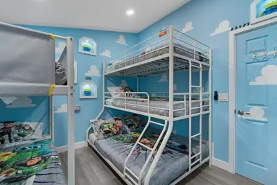 a bedroom with two bunk beds and a blue wall at Pixar Pier by OC Adventure Homes in Anaheim