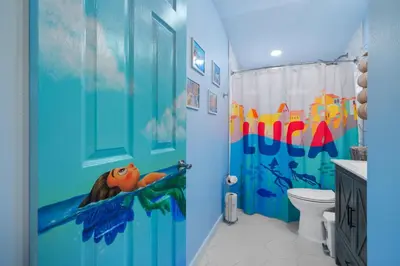 a bathroom with a ocean themed shower curtain at Pixar Pier by OC Adventure Homes in Anaheim