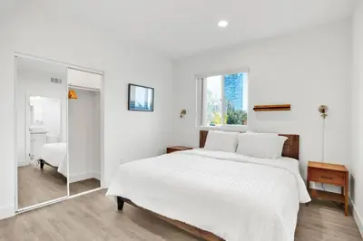 a white bedroom with a large bed and a mirror at Modern Rooftop Villa in Los Angeles