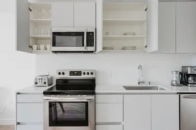 a white kitchen with a microwave and a stove at Blueground Pasadena gym elev near bars LAX-1231 in Los Angeles