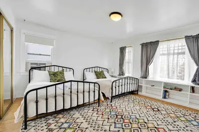 two beds in a room with windows and a rug at Classic Home Near Downtown & Hollywood in Los Angeles