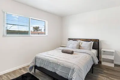 a white bedroom with a large bed with a window at Cozy House Minutes From Downtown in Los Angeles