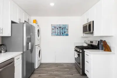 a kitchen with white cabinets and a stainless steel refrigerator at Cozy House Minutes From Downtown in Los Angeles