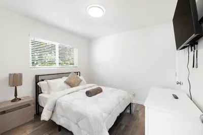 a white bedroom with a bed and a tv at Cozy House Minutes From Downtown in Los Angeles