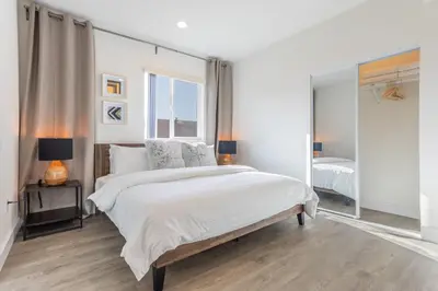 a white bedroom with a large bed and a mirror at LA Cityscapes in Los Angeles