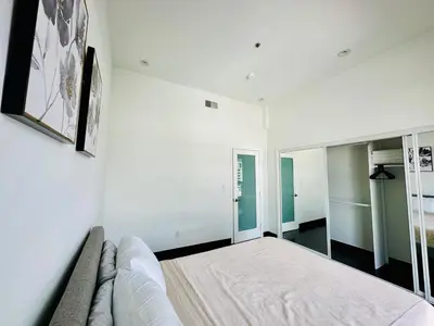 a white bedroom with a bed and a mirror at Cool Apartment in West Hollywood in Los Angeles