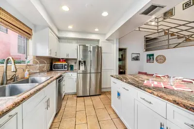 a kitchen with white cabinets and a stainless steel refrigerator at House on the canal in Venice in Los Angeles