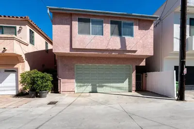 a house with a green garage door in a driveway at House on the canal in Venice in Los Angeles