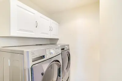 a white laundry room with a washing machine and white cabinets at 2 Mi to Ocean Long Beach Home with Gas Grill! in Long Beach