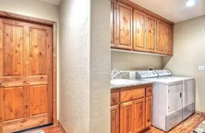a kitchen with a washing machine and wooden cabinets at Arctic Wolf at Summit Base - 4 Bedroom log cabin at the base of Snow Summit in Big Bear Lake