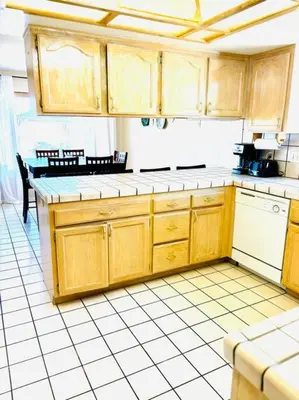 a kitchen with wooden cabinets and a white tiled floor at Silver Lakes Oasis with Resort Style Amenities in Helendale
