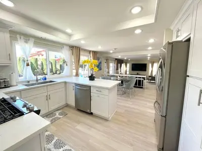 a kitchen with white cabinets and a kitchen with yellow flowers at Family Paradise near Disneyland with Sparkling Pool in Del Prado Bolsa