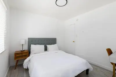 a white bedroom with a bed and a clock on the wall at Sunny 1 Bedroom in the Heart of Venice Beach - #1 in Los Angeles
