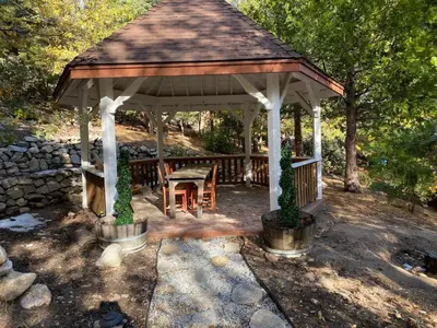 a wooden gazebo with a table and a bench at Gingerbread Gardens in Twin Peaks