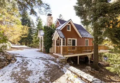 a house with a wrap around deck in the woods at Gingerbread Gardens in Twin Peaks