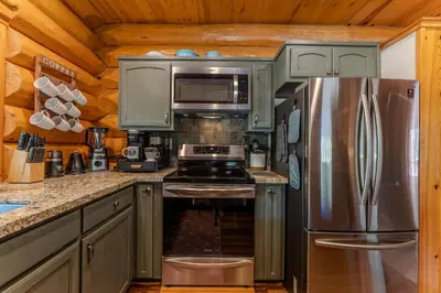 a kitchen with a stainless steel refrigerator and cabinets at Peppermint Falls Ranch in Ponderosa