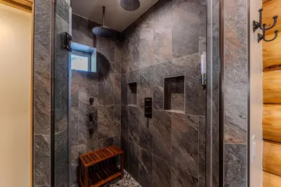 a walk in shower in a bathroom with a stone wall at Peppermint Falls Ranch in Ponderosa