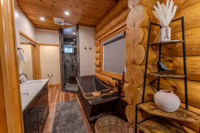 a log cabin bathroom with a sink and a window at Peppermint Falls Ranch in Ponderosa