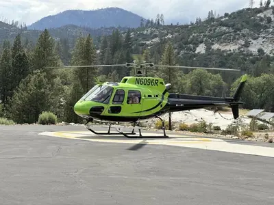 a green helicopter is parked on a runway at Peppermint Falls Ranch in Ponderosa