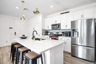 a kitchen with white cabinets and a stainless steel refrigerator at Charming Home Near Six Flags in Santa Clarita