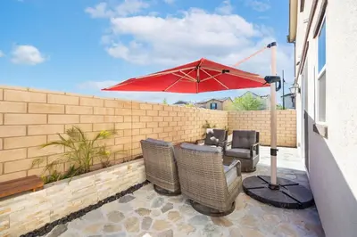 a patio with two chairs and a red umbrella at Charming Home Near Six Flags in Santa Clarita