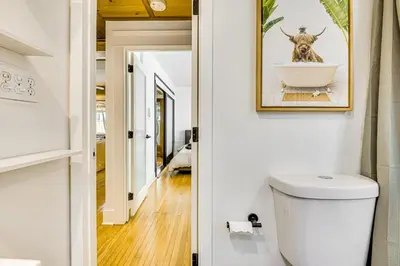 a bathroom with a toilet and a picture of a cow in a tub at Walk to Abbot Kinney Tranquil Cottage in Venice! in Los Angeles