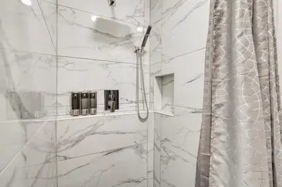 a bathroom with a shower with white marble walls at 2 Mi to Water Lake Arrowhead Studio in Lake Arrowhead