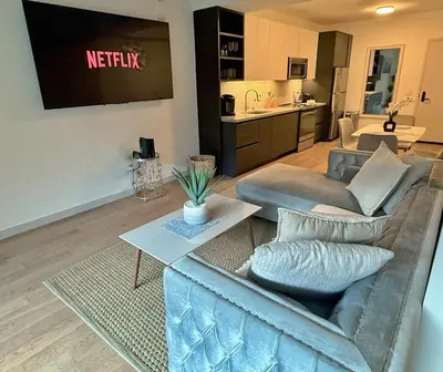 a living room with a couch and a tv at Hollywood Luxury Retreat I Pool Views I Jacuzzi I Fitness Center I Free Parking! in Los Angeles