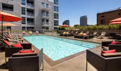 a swimming pool with chairs and umbrellas on a building at Hollywood Luxury Retreat I Pool Views I Jacuzzi I Fitness Center I Free Parking! in Los Angeles
